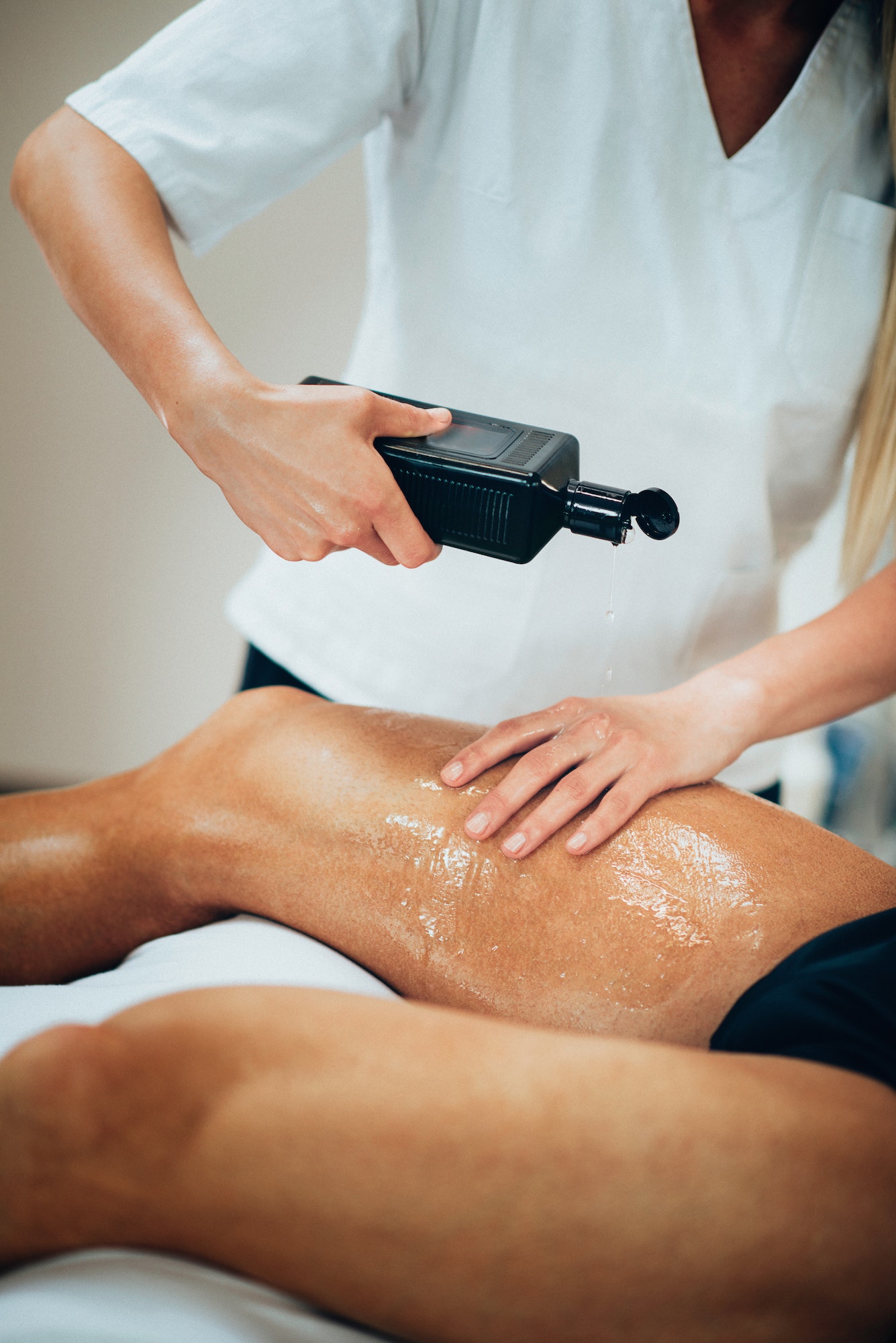 Sports massage. Therapist pouring massage oil